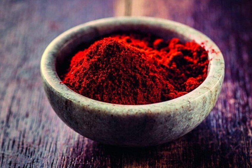 A wooden bowl filled with red powder on a wooden surface. 3