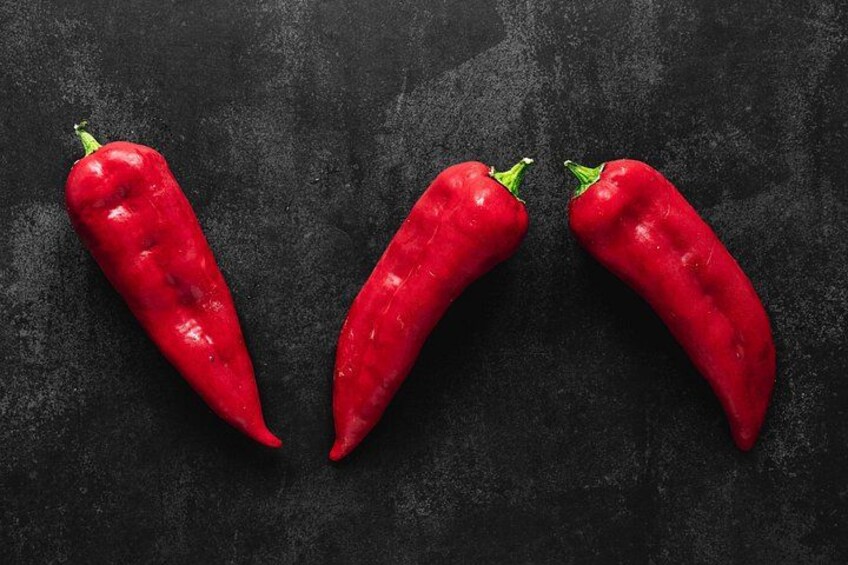 Three red chili peppers on a dark surface. 2