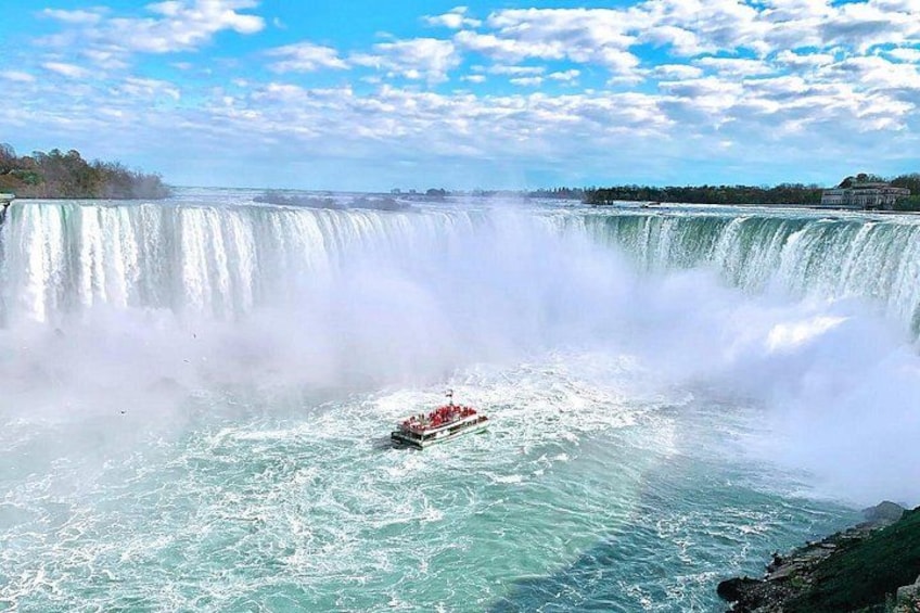 A boat navigating a large waterfall, surrounded by water spray and a clear sky. 2