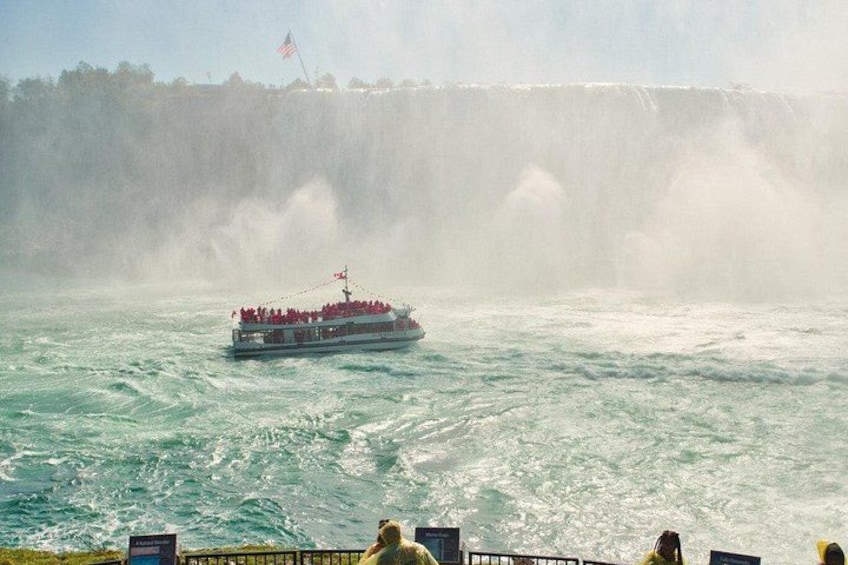 A boat with passengers on a river with a waterfall in the background. 5