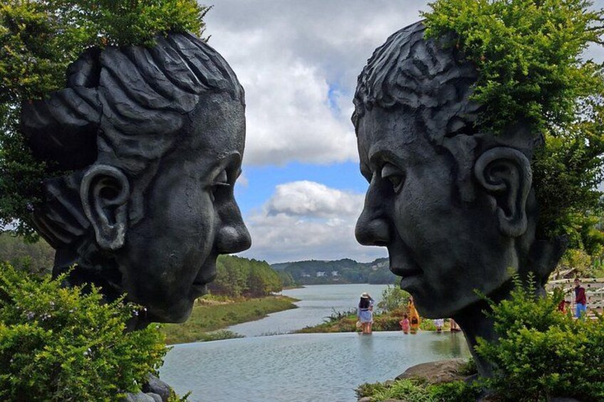 A statue of two figures facing each other with a river and mountains in the background. 3