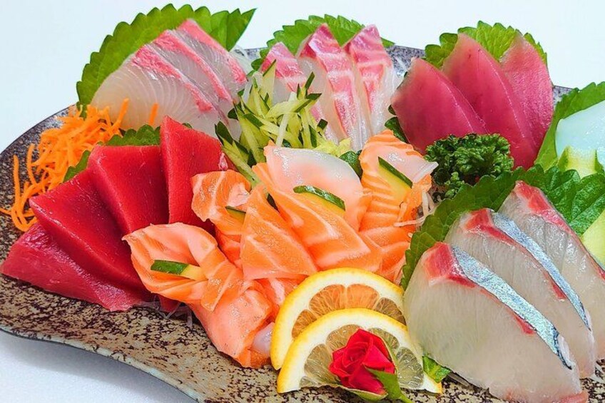 A variety of sashimi and sushi on a ceramic plate. 4