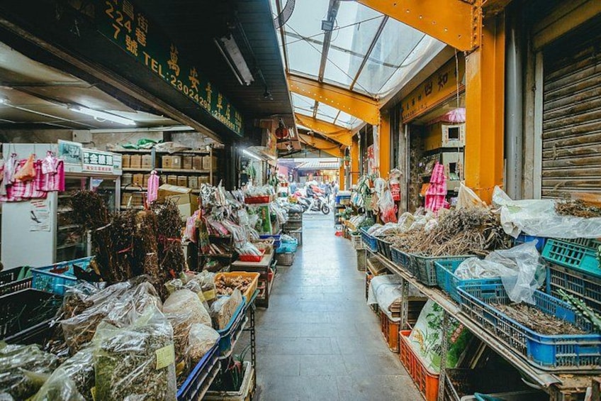 A market aisle with various goods displayed on tables and shelves. 3