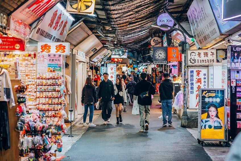 A crowded indoor market with various shops and signs in a foreign language. 2