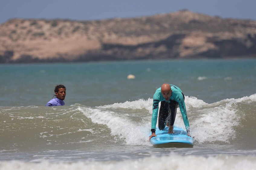 A person surfing on a wave with a rocky coastline in the background. 4