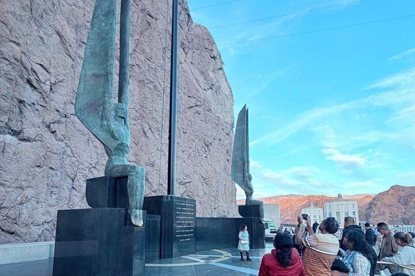 A monument with two large figures, a clear sky, and a mountainous landscape in the background. 2