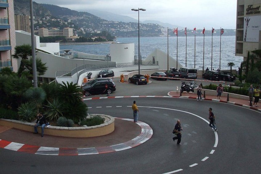 Una glorieta con coches y peatones, un cuerpo de agua y edificios al fondo. 4