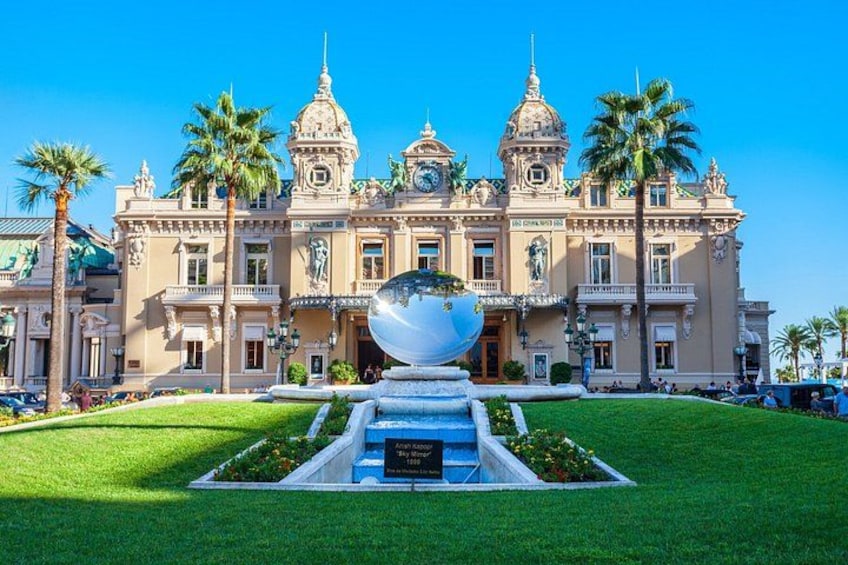 Un edificio imponente con una fuente central, palmeras y un cielo azul despejado. 5