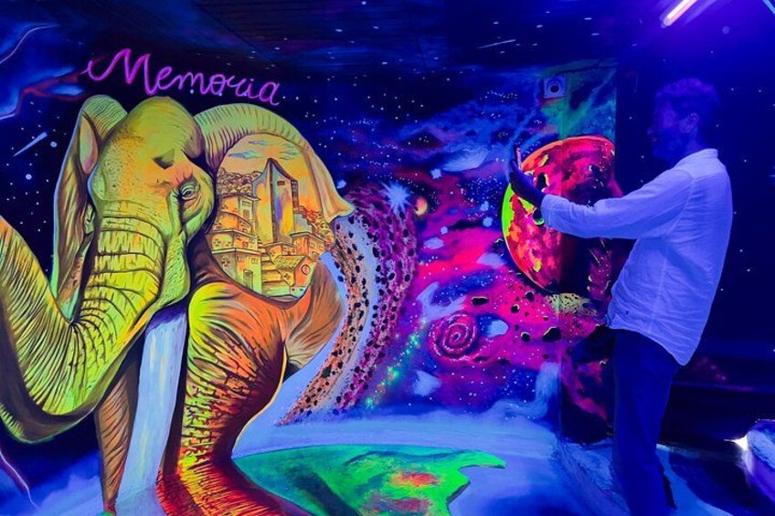 A person interacting with a colorful, illuminated wall featuring elephants and a cityscape. 5