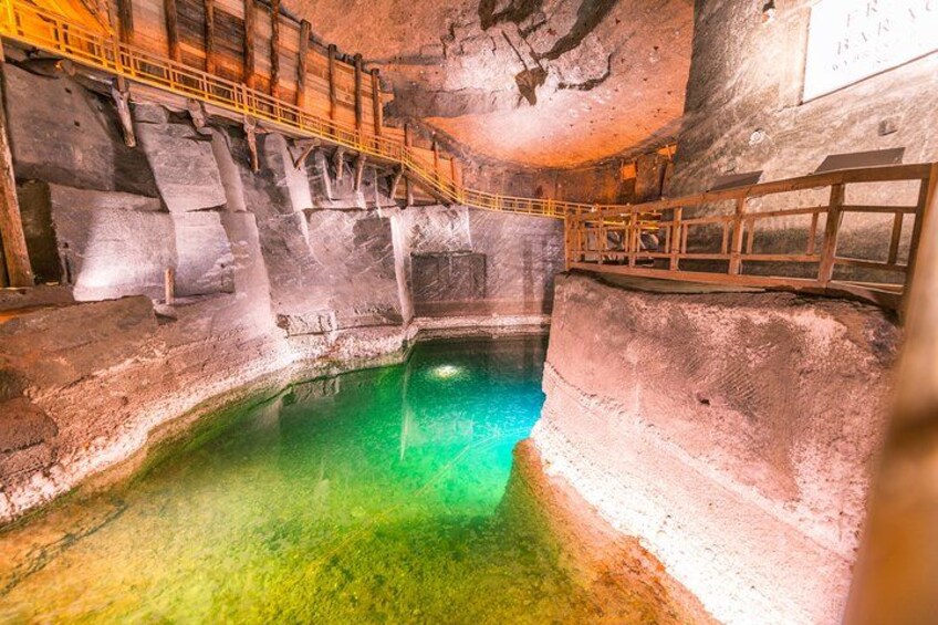 A cave with a pool of water, wooden railings, and a sign. 2