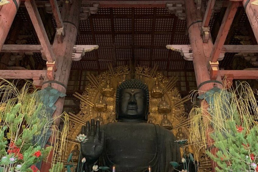 A large Buddha statue in a temple with a wooden roof and golden decorations. 2