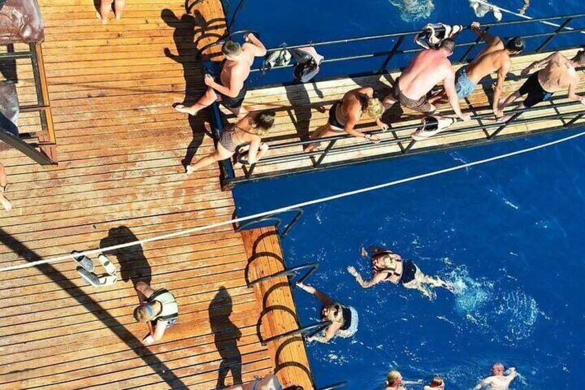 Mensen op een houten terras en in het water, sommigen in zwemkleding en anderen in casual kleding. 5