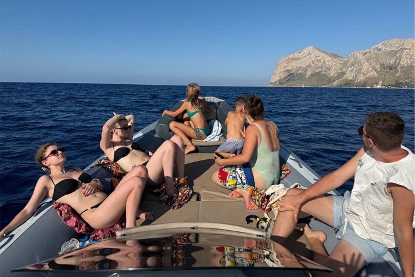 A group of people on a boat with rocky cliffs in the background. 2