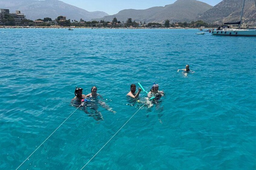 People snorkeling in clear blue water with mountains in the background. 2