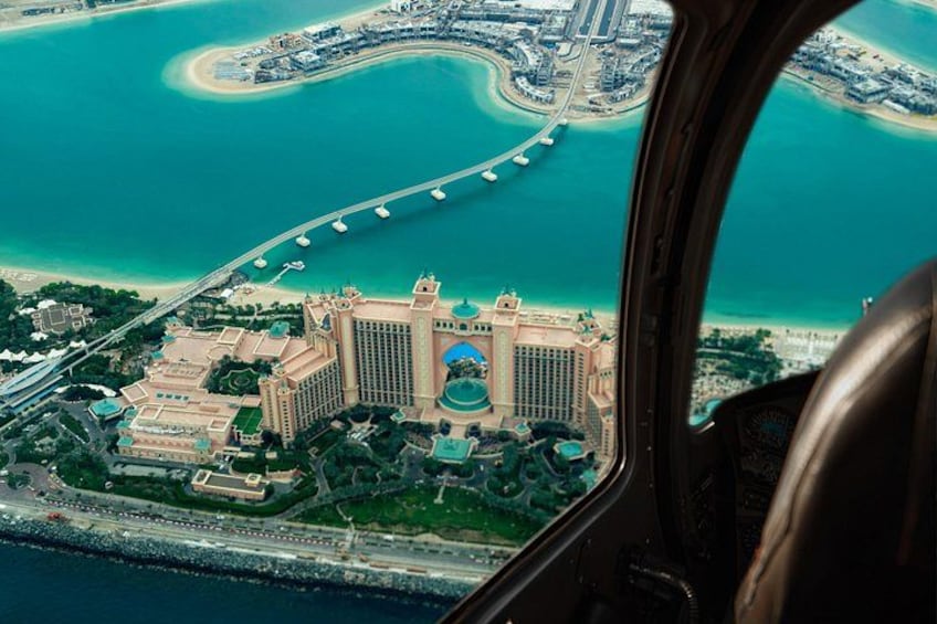 An aerial view of a coastal city with a prominent hotel, a bridge, and a marina. 4