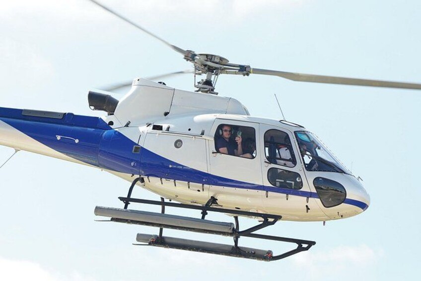 A helicopter with two passengers, flying in clear sky. 5