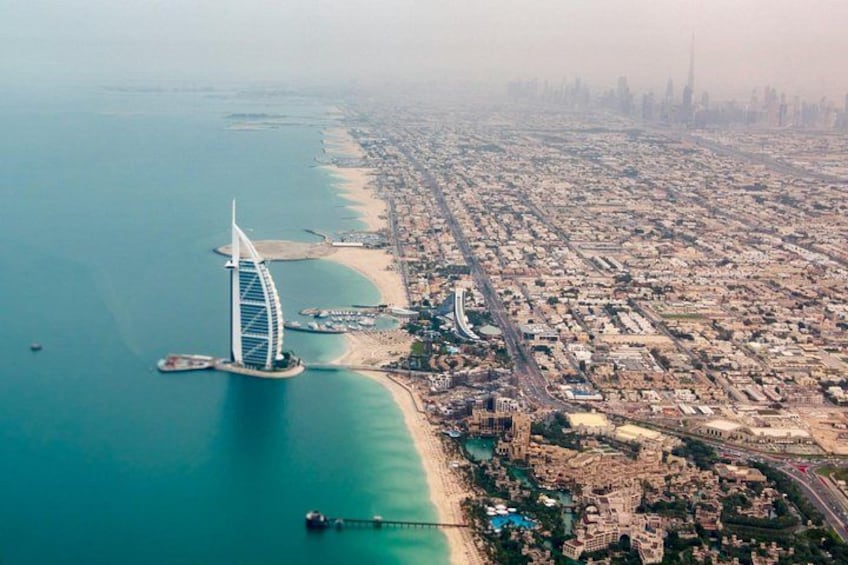 A coastal city with a prominent modern tower, a beach, and a dense urban area. 2