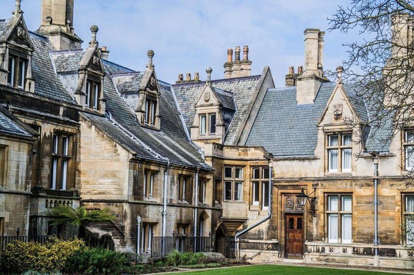 A historic stone building with multiple chimneys, a central entrance, and a well-maintained garden. 3