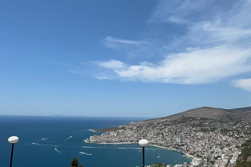 A coastal cityscape with a mountain in the background, a clear sky, and a body of water. 1