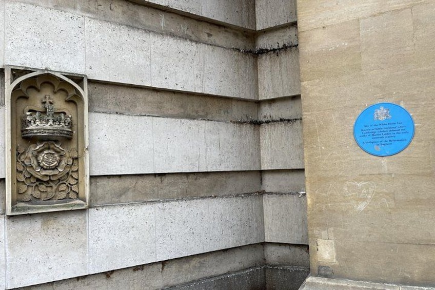 A stone wall with a carved crest and a blue plaque. 4