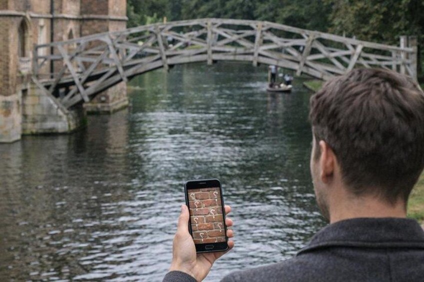 A person holding a smartphone, a bridge, and a boat on a river. 2