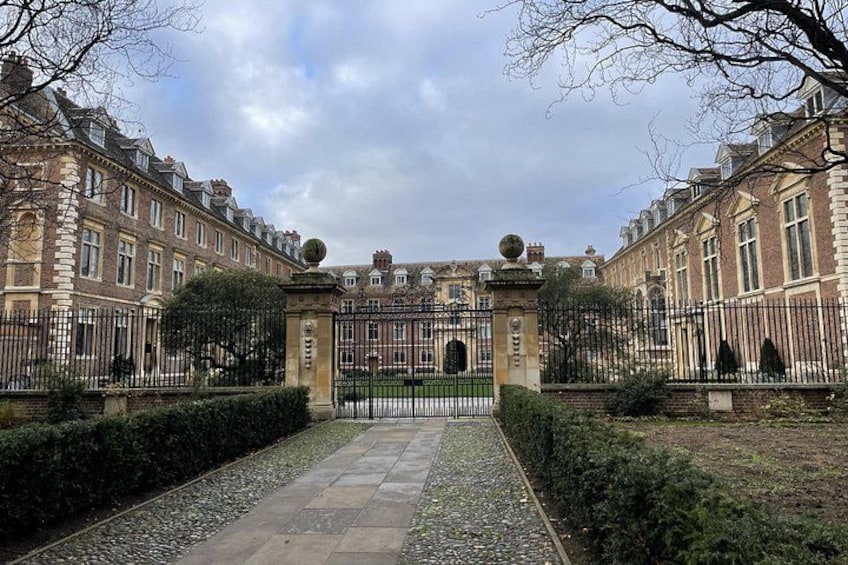 A formal entrance with a gate, manicured hedges, and a paved pathway leading to a building with symmetrical architecture. 5