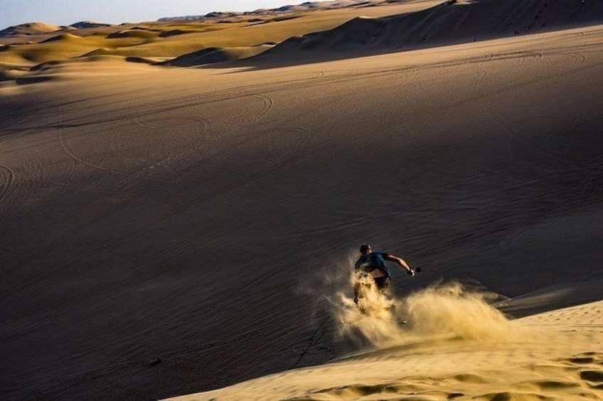 A person riding a dune buggy on a vast sandy dune landscape. 3