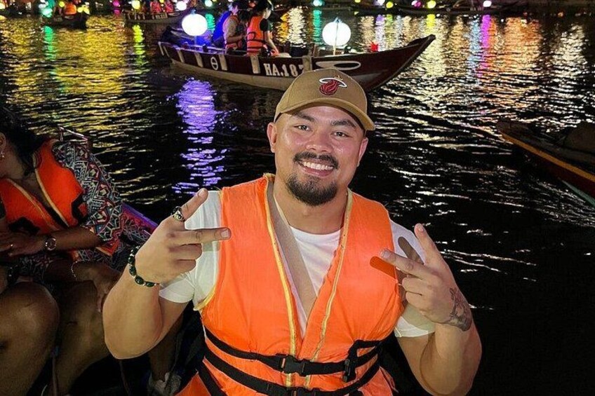 A person in a life jacket on a boat with colorful lights in the background. 2