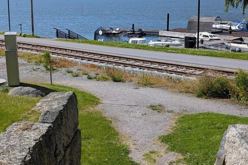 A railway track, a grassy area, a stone wall, and a body of water with boats. 4