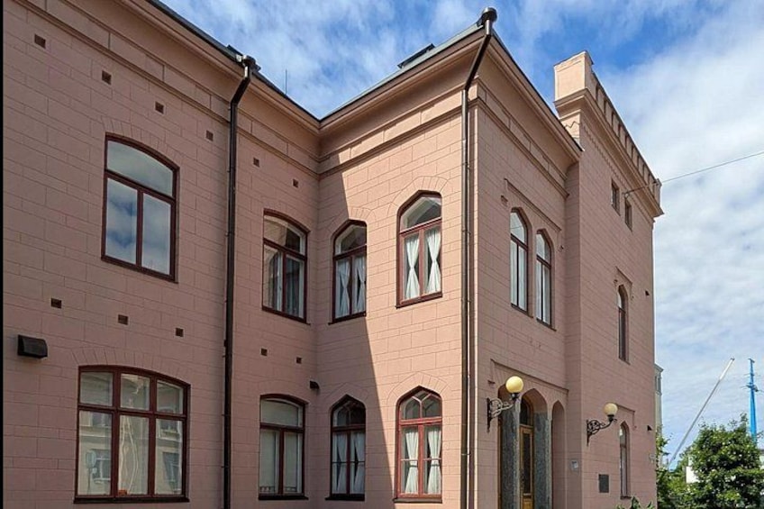 A pink brick building with arched windows and a corner entrance. 2