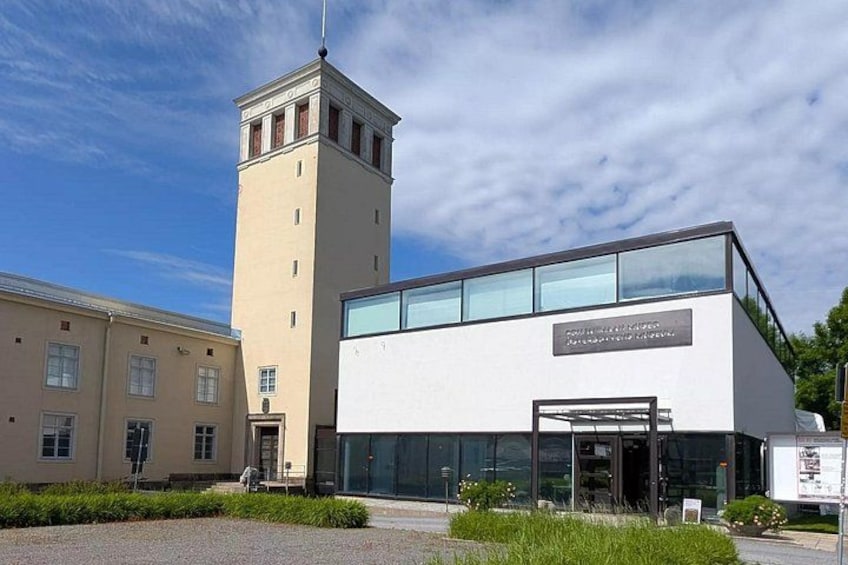 A modern building with a tower, a glass entrance, and a sign. 3