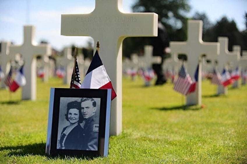 Un cimitero con croci e bandiere americane, una foto incorniciata e un cielo sereno. 5