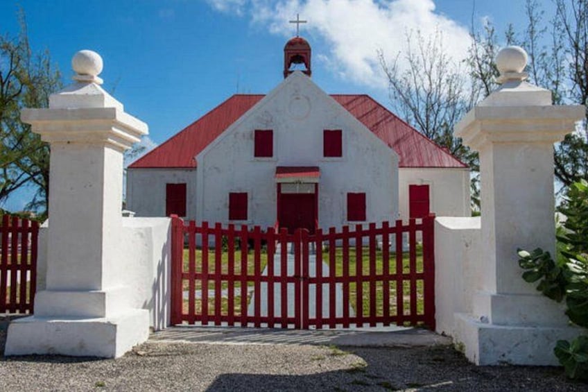 A white church with a red roof and a red gate. 3