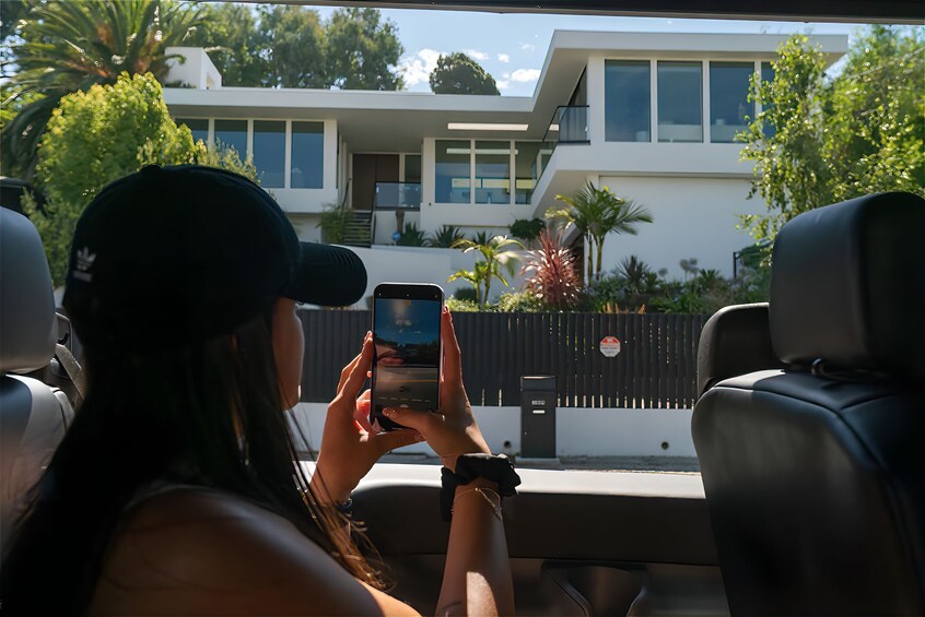 Eine Person fotografiert ein modernes Haus mit einem Balkon. 2