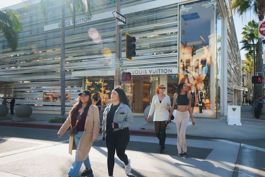 Fußgänger überqueren eine Straße vor einem Louis Vuitton Geschäft. 3