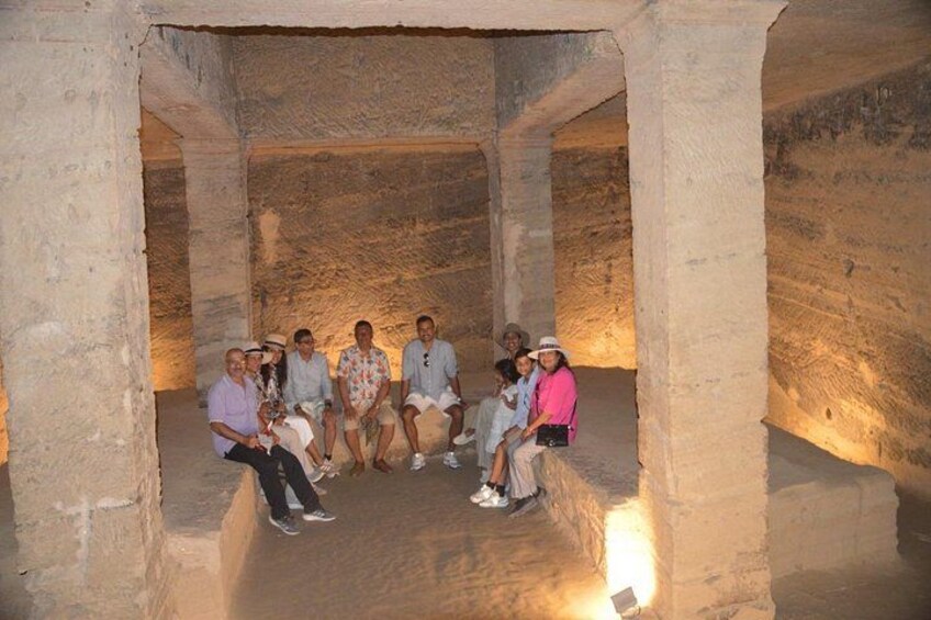 Un grupo de personas sentadas en una edificación de piedra con una luz cálida. 5