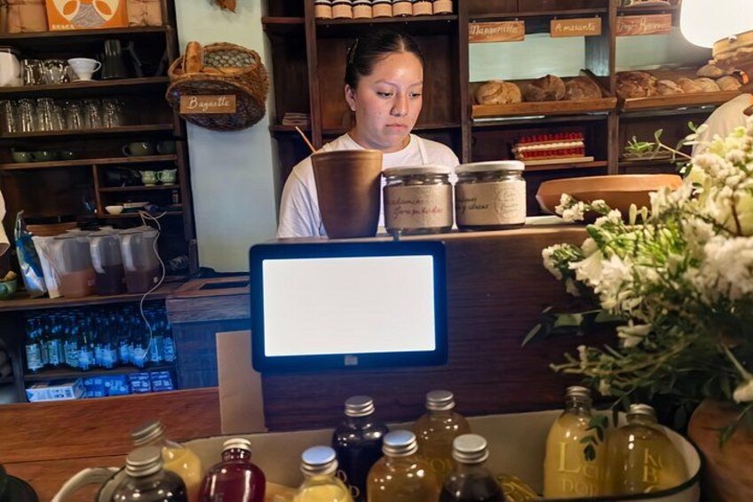 A bakery counter with jars of honey and a computer monitor. 2