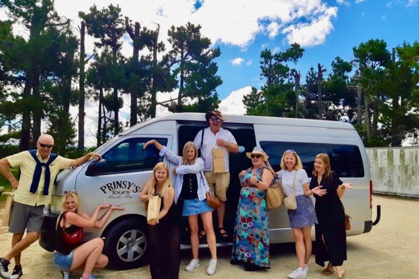 A group of people posing in front of a van with 'PRINSY'S TOURS' written on it. 1