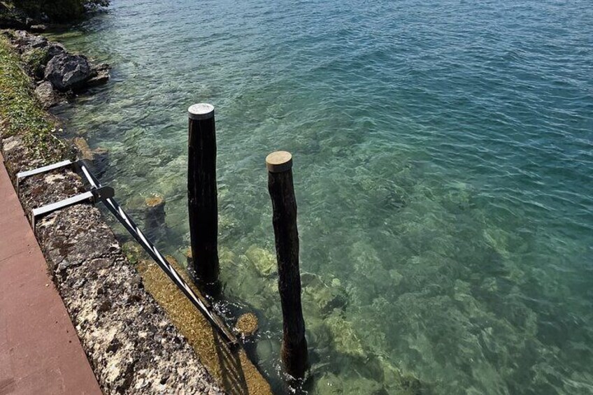A clear water body with two wooden posts and a metal railing along the edge. 3
