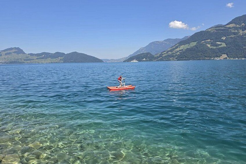 A kayaker in a red kayak on a calm lake with clear water and mountains in the background. 5