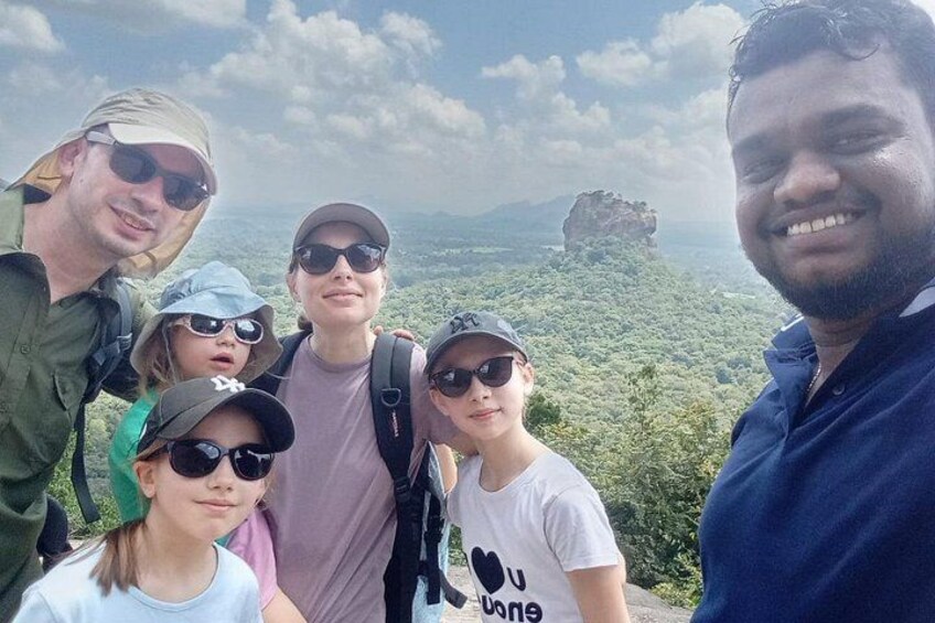 En grupp människor på ett berg, med klar himmel och en klippformation i bakgrunden. 1