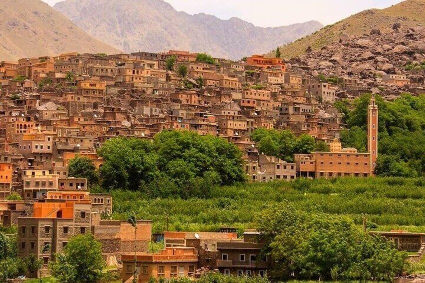 A densely packed hillside village with traditional buildings and a prominent minaret. 1