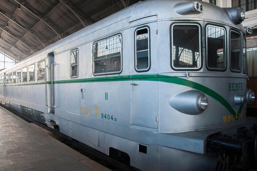 A silver train with green stripes and the number 9404x at a station. 4
