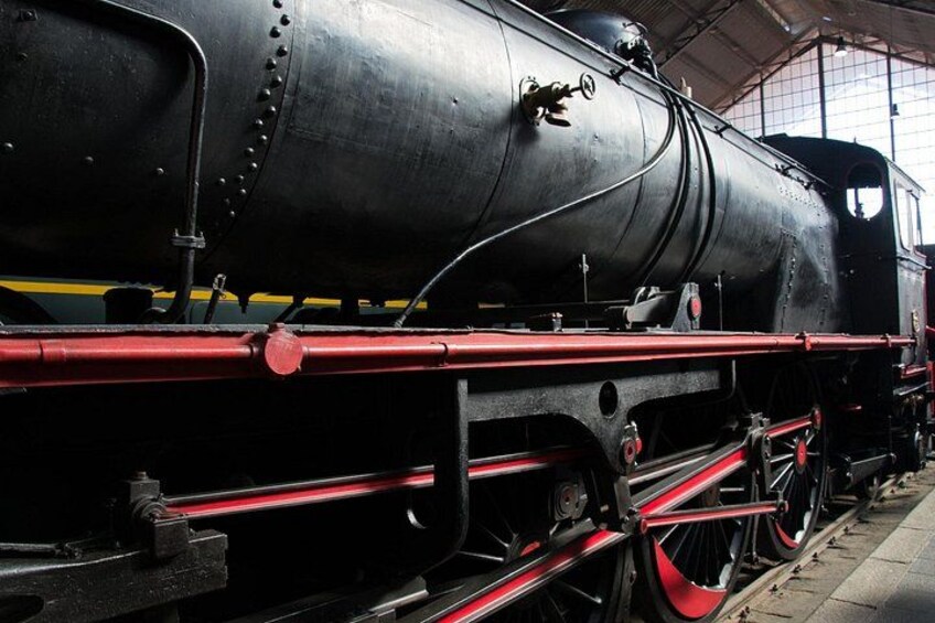 A black steam locomotive with red wheels and a red stripe along the side. 5