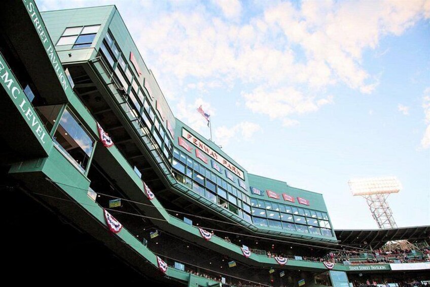 A multi-level stadium with green architecture, American flags, and a large scoreboard. 3