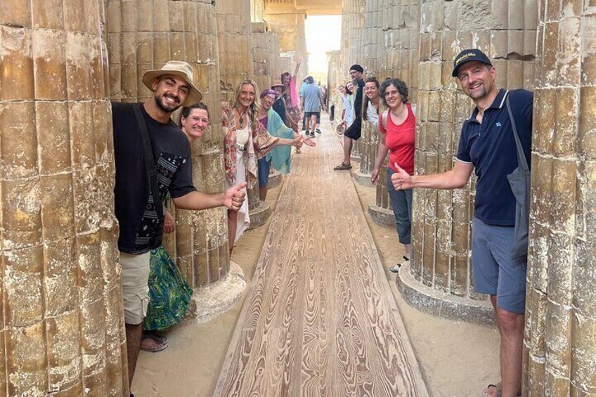 Un grupo de personas caminando por un pasillo con paredes de piedra y un suelo estampado. 1