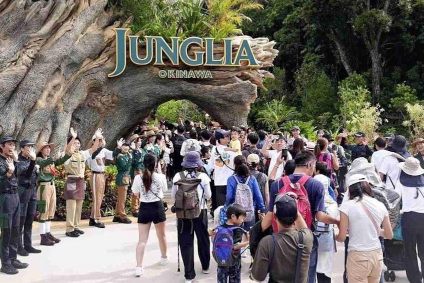 A crowd at the entrance of Jungle Okinawa, with a large rock structure and lush greenery. 2