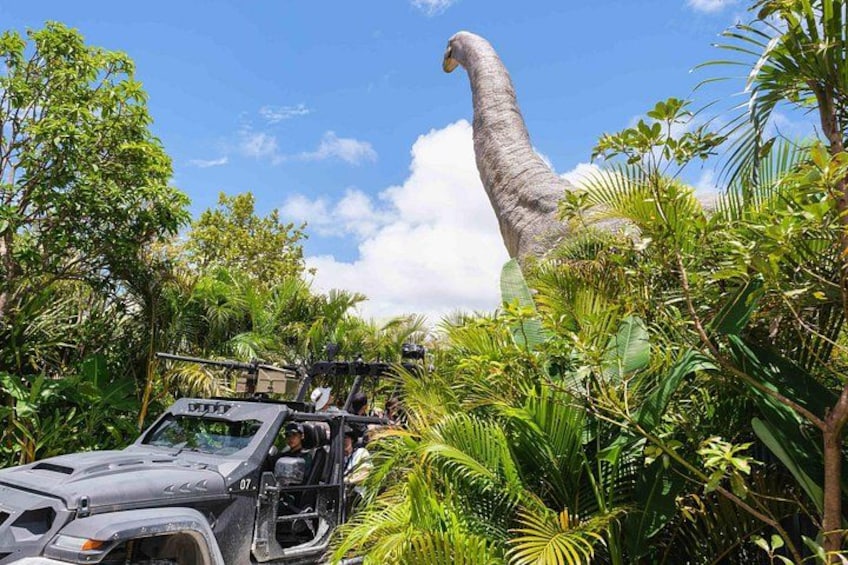 A vehicle with a large dinosaur model in a lush green environment. 5