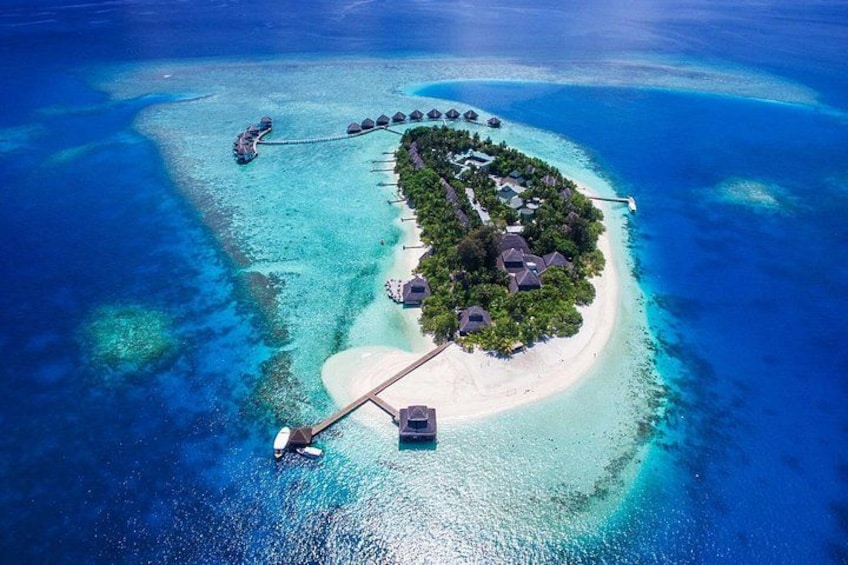 An aerial view of a tropical island with clear turquoise waters, a white sandy beach, and overwater bungalows connected by a bridge. 1