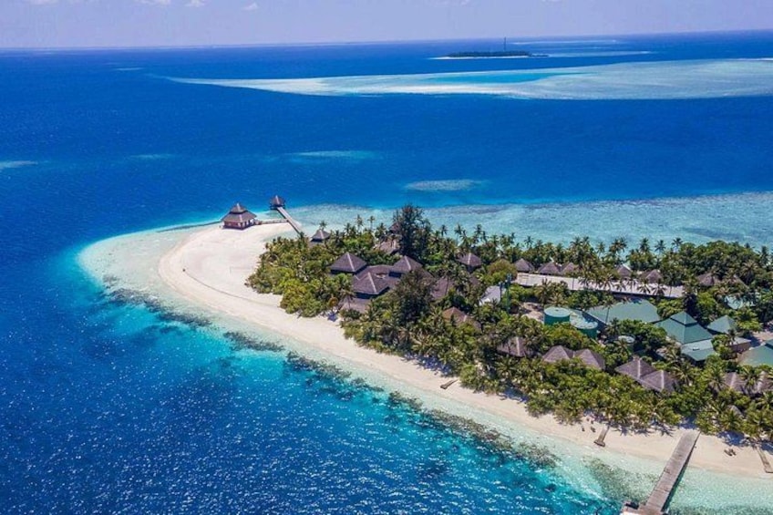 An aerial view of a tropical island resort with overwater bungalows, clear turquoise waters, and a sandy beach. 3